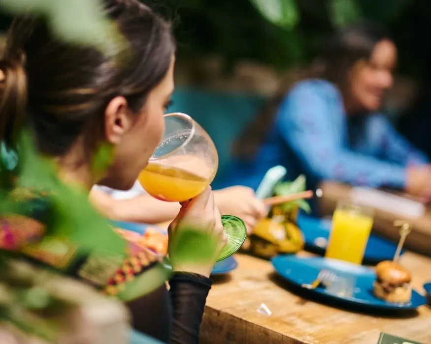 Mujer bebiendo un vaso de jugo de naranja, disfrutando de la bebida refrescante