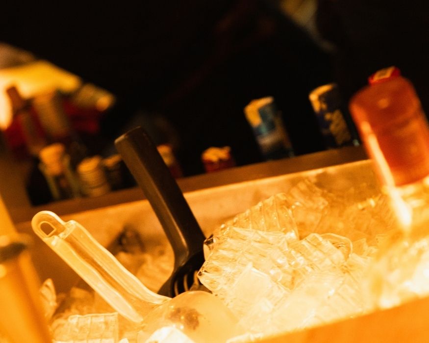 A well-stocked bar featuring ice and an assortment of alcohol bottles on display