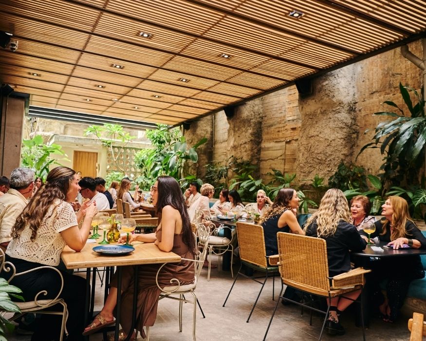 A restaurant scene with people enjoying meals at tables, enhanced by decorative indoor plants